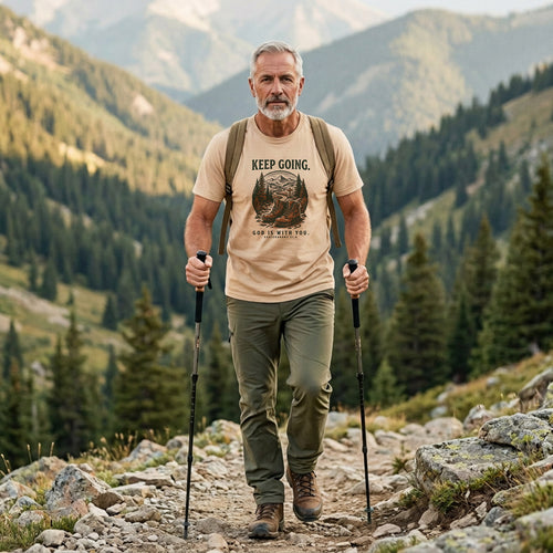 Man hiking in an Ivory Keep Going Christian t-shirt on a mountain trail