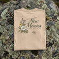 Folded Ivory New Mercies t-shirt showing the daisy and wildflower back print on a lichen-covered rock
