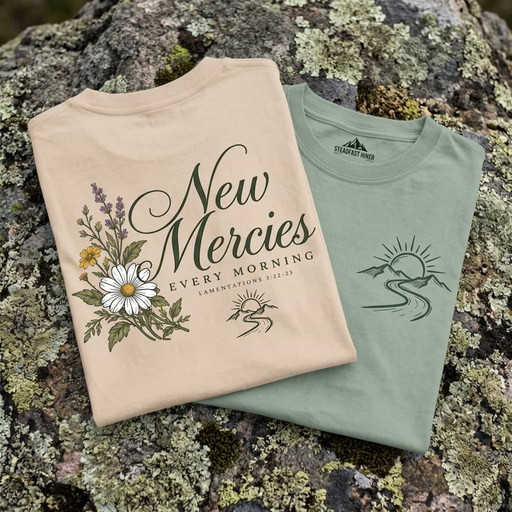 New Mercies Lamentations 3:22-23 t-shirt folded in Ivory and Bay on a mossy granite boulder
