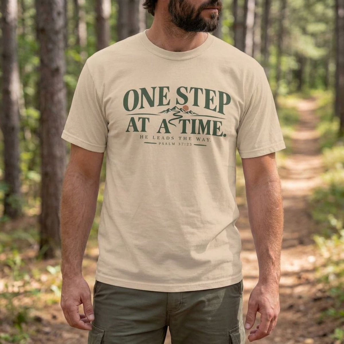 Man hiking in an  Ivory One Step at a Time Christian t-shirt on a mountain trail