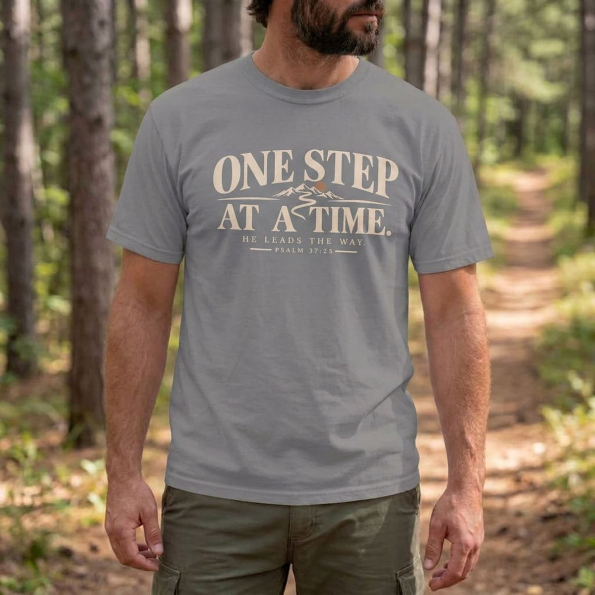 Man hiking in a Gray One Step at a Time Christian t-shirt on a mountain trail
