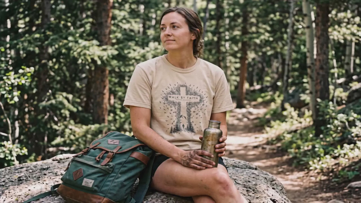 Video of woman wearing Walk by Faith Christian t-shirt resting on a forest trail