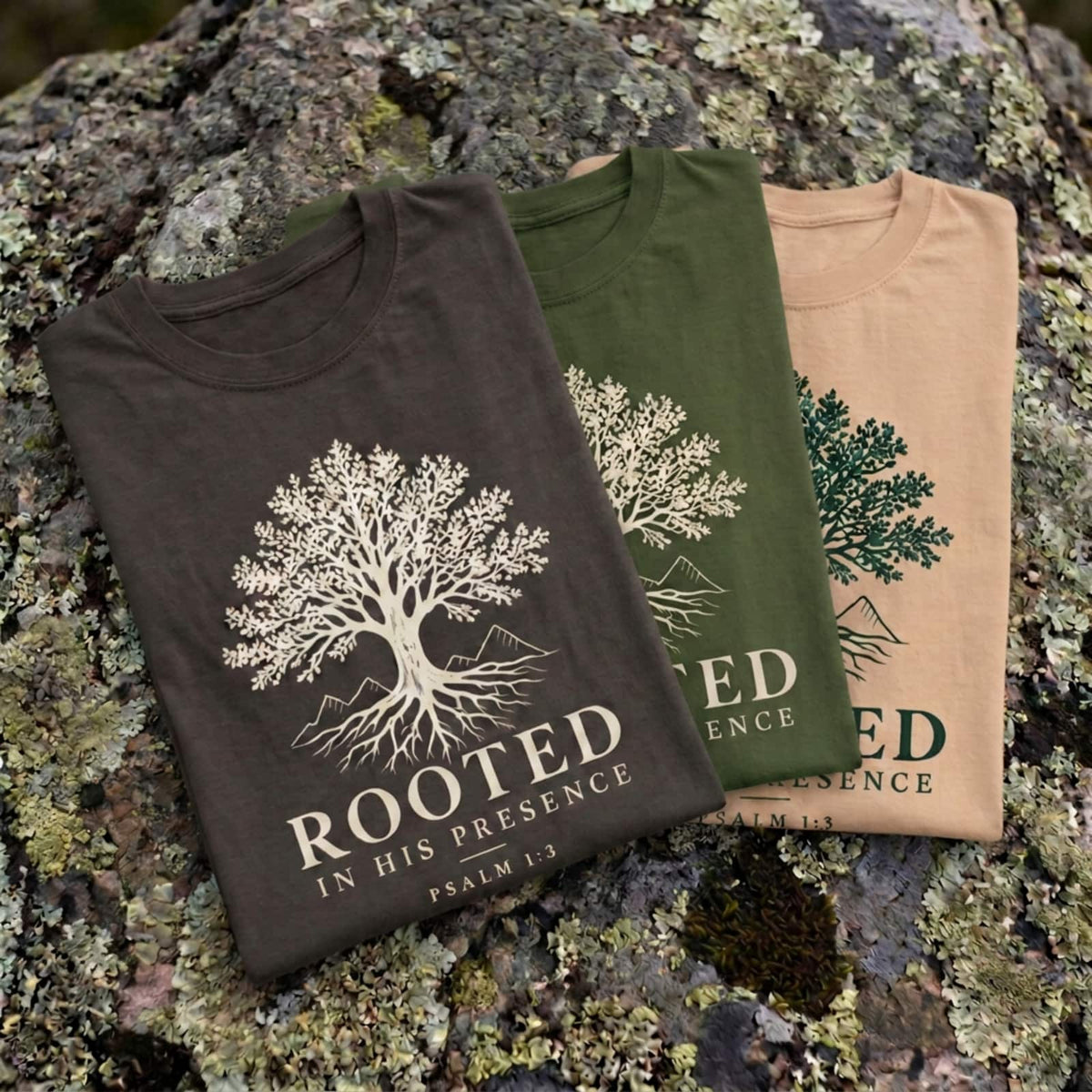 Rooted Psalm 1:3 t-shirt folded in Pepper, Sage and Ivory on a mossy granite boulder