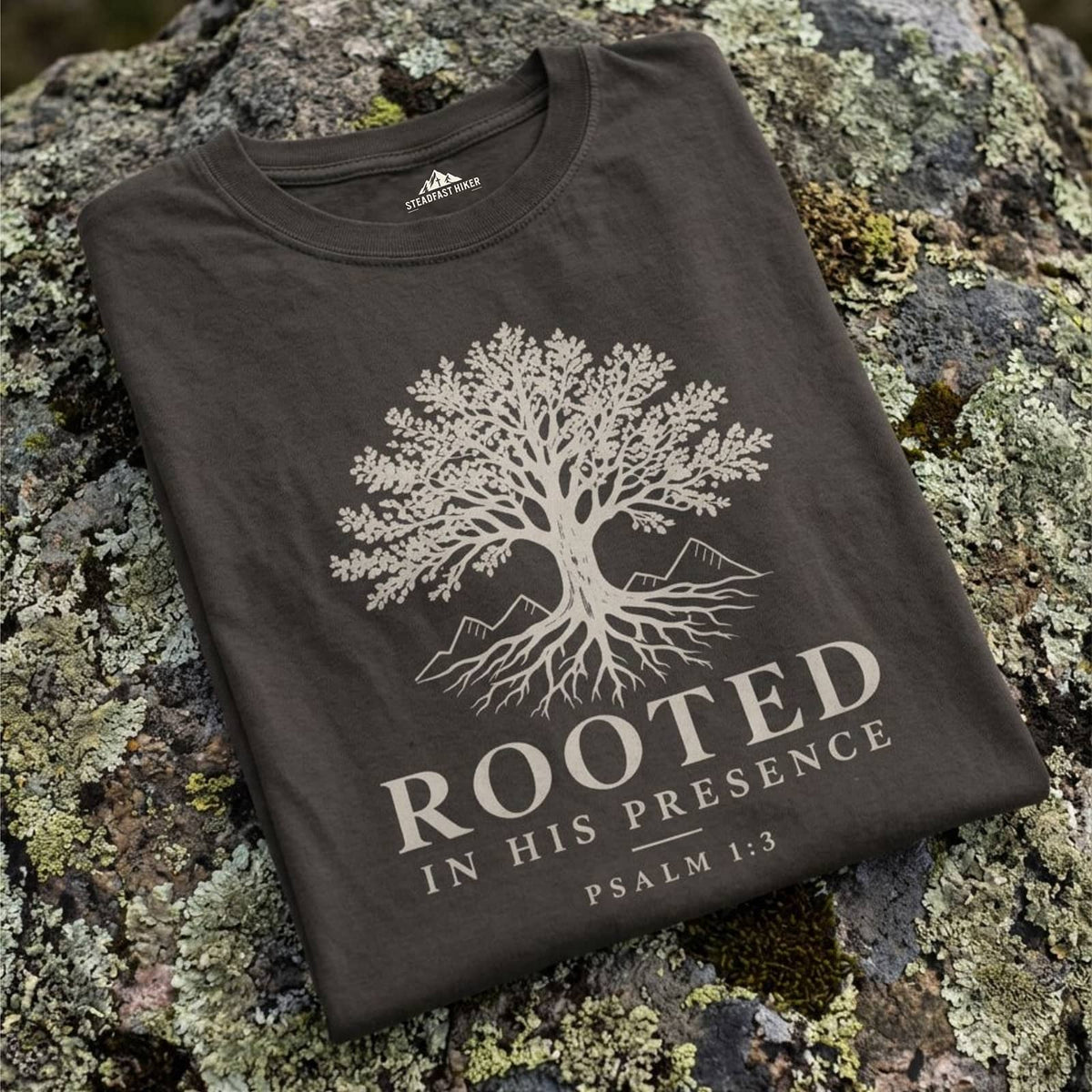 Folded Pepper Rooted In His Presence t-shirt with cream tree design on a lichen-covered mountain rock