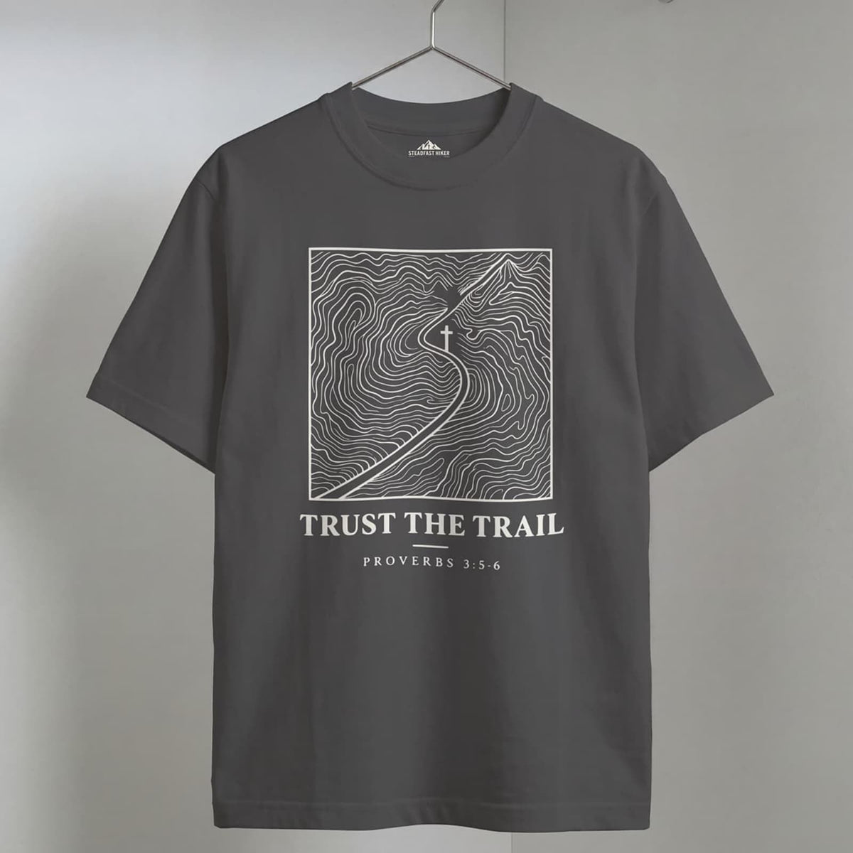 Pepper Trust the Trail Christian hiking t-shirt on a wooden hanger