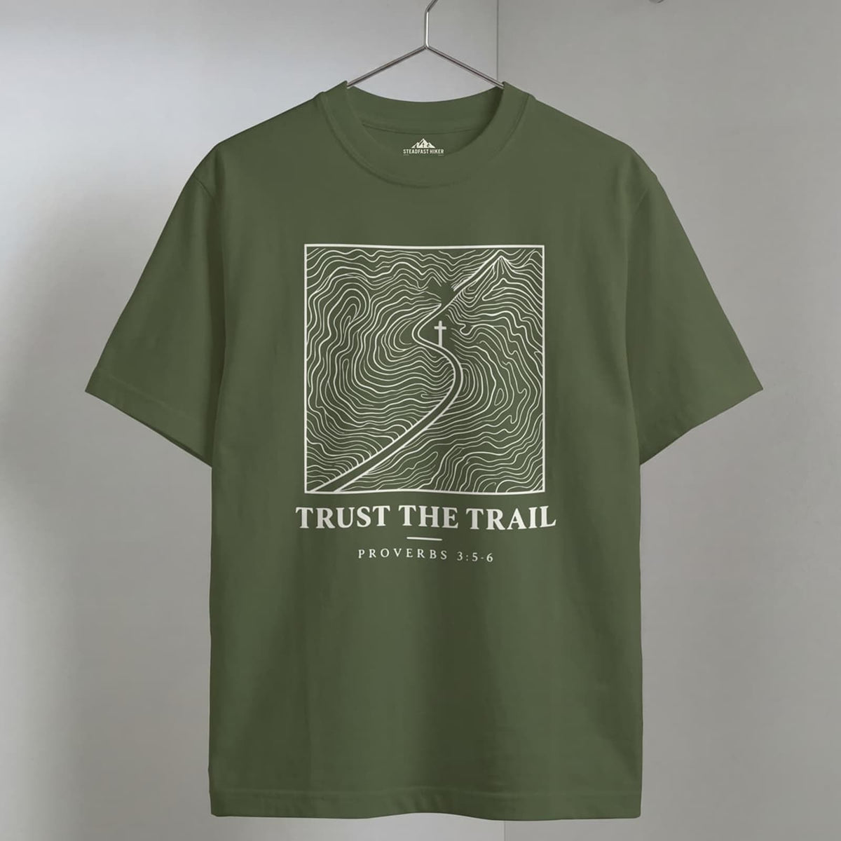 Sage Trust the Trail Christian hiking t-shirt on a wooden hanger, Proverbs 3:5-6