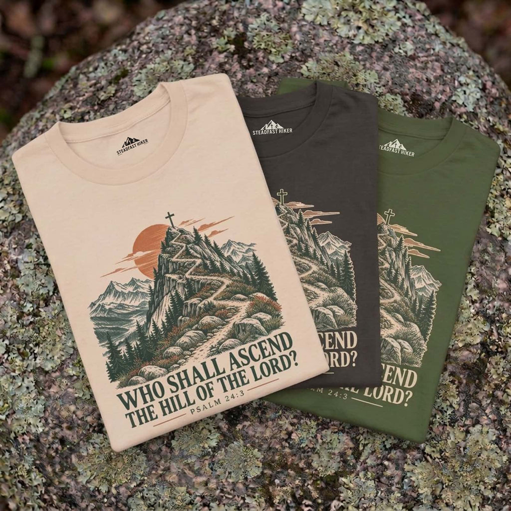 Who Shall Ascend Christian hiking t-shirts in Ivory, Pepper and Sage laid on a rock