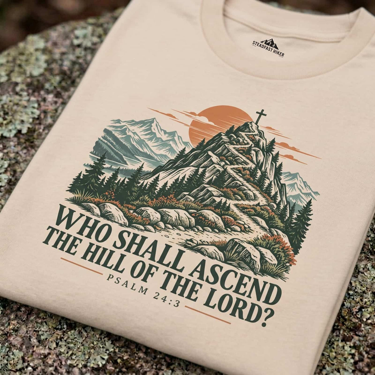 Close-up of the Who Shall Ascend mountain trail design printed on an Ivory Christian hiking t-shirt resting on a rock, Psalm 24:3